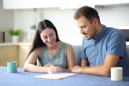 Happy interracial roommates or couple signing contract in the kitchen at homeの写真素材