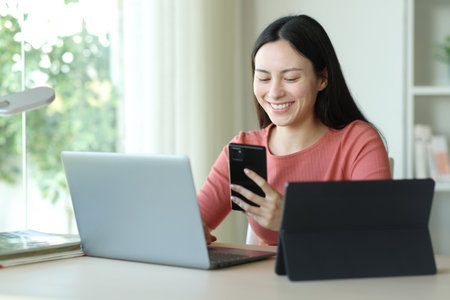 Happy asian woman using multiple devices sitting in a room at homeの写真素材