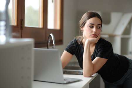 Distracted woman with a laptop looking away in a house under renovationの写真素材