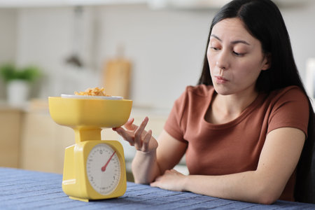 Asian woman weighing food in the kitchen at homeの写真素材