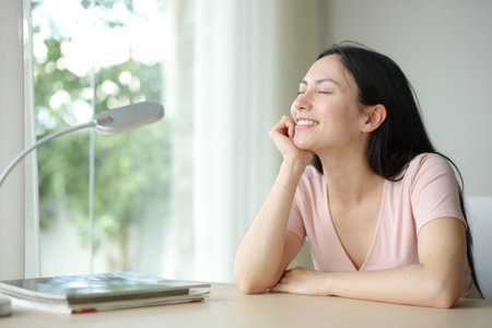 Happy asian woman smiling relaxing on a desk in a room at homeの写真素材