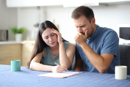 Sad interracial couple or roommates reading contract in the kitchen at homeの写真素材