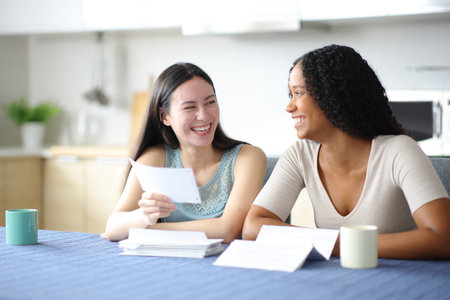 Interracial roommates checking bank statement in the kitchen at homeの写真素材
