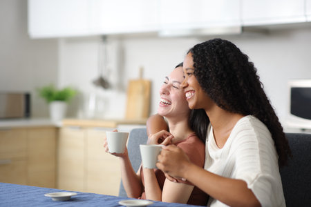 Happy interracial lesbian couple enjoying in the kitchen at homeの写真素材