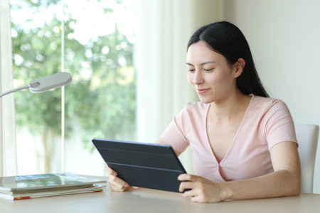 Asian woman watching media on tablet in a room at homeの写真素材