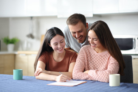 Happy roommates signing lease contract in the kitchen at homeの写真素材