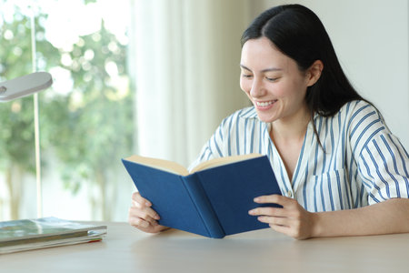 Happy asian woman reading paper book in a room at homeの写真素材