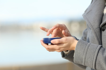 Close up of woman hands applying moisturizer cream on the beach in winterの写真素材