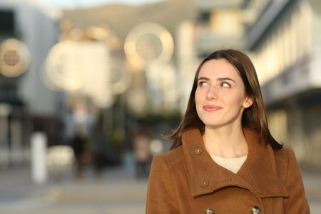 Front view portrait of a happy beautiful woman in winter looking at side in the streetの写真素材