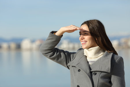 Happy woman in winter protecting from sun with handの写真素材
