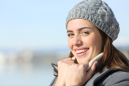 Happy woman with perfect smile in winter looking at you keeping warmの写真素材
