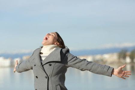 Excited woman in winter outstretching arms and screamingの写真素材
