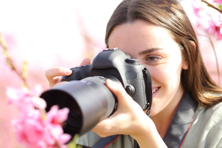 Woman using dslr camera to take macro photo in a flowered fieldの写真素材
