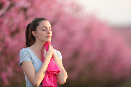 Sportswoman drying sweat with a towel in nature at sunsetの写真素材