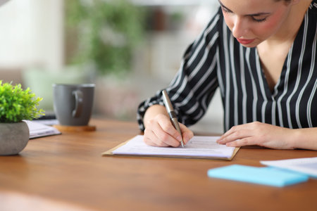 Self employed filling out form on wooden desktop working at home
