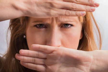 angry female face covered with handsの写真素材