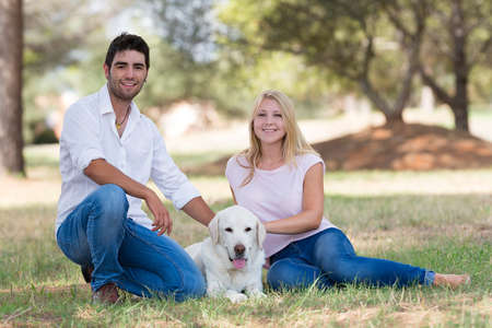 young couple relaxing with old senior labrador dog in the nature,selective focusの写真素材