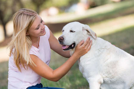 blond teenager with fourteen years old  labrador dog in the park, selective focusの写真素材