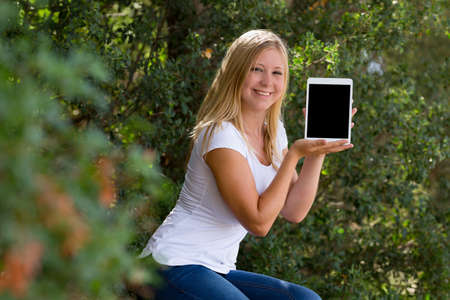 blond young women showing digital tablet outdoor,selective focusの写真素材