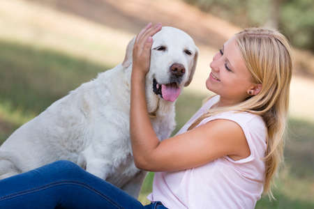 young woman with old senior labrador dog in the park, selective focusの写真素材