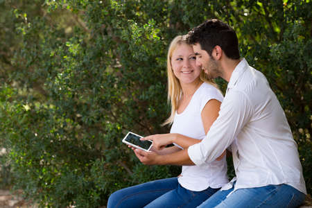 young couple using internet outdoor with digital tabletの写真素材