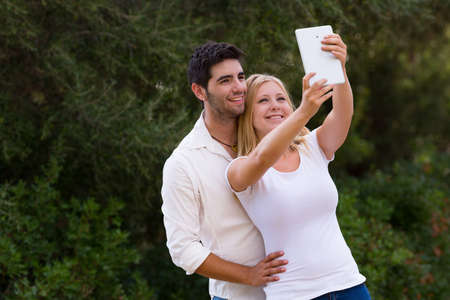 couple taking selfie photo with digital tablet, camera hole moved from the corner to the center on the topの写真素材