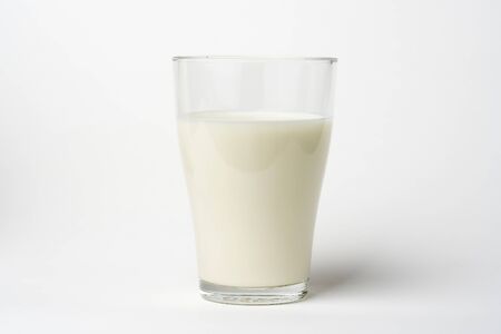 pouring fresh glass of milk isolated over whiteの写真素材