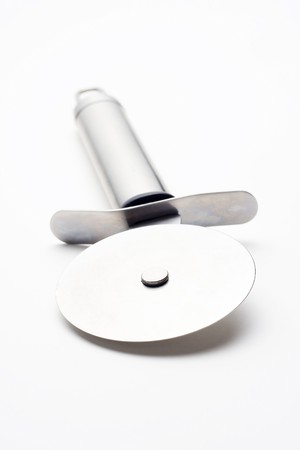 shiny metal pizza cutter isolated over whiteの写真素材