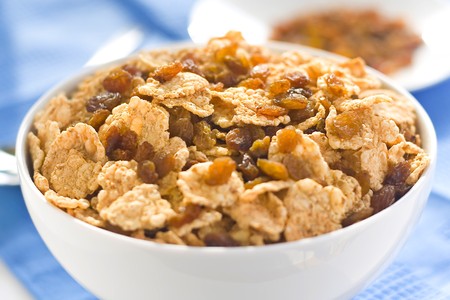 bowl of cereal with raisins, milk and orange juice
