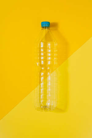 Vertical color image with an overhead view of a clear plastic bottle with blue cap on a yellow...