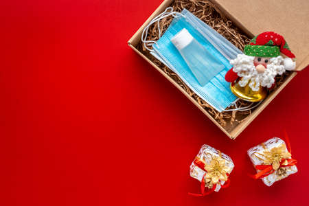 Face masks and hydroalcoholic gel inside a cardboard box decorated with a bow on redの写真素材