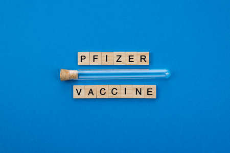 Horizontal color image with a front view of a vaccine 90% effective against the coronavirus pandemic written with wooden letters on a blue background. Covid concept.の写真素材