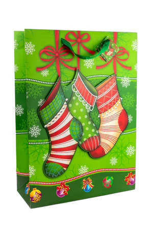 Horizontal color image with a front view of a green Christmas shopping bag made of paper decorated with Christmas socks on a white background. New year and gifts concept.の写真素材