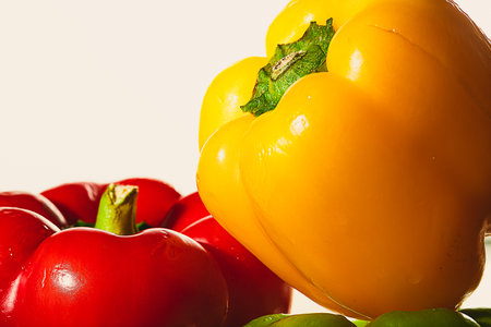 detail of freshly cut red, yellow and green peppers on a white background with natural light glittering on themの写真素材