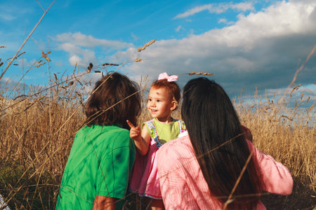 Little caucasian redhead girl smiling and pointing at the horizon with her family wearing pink and...