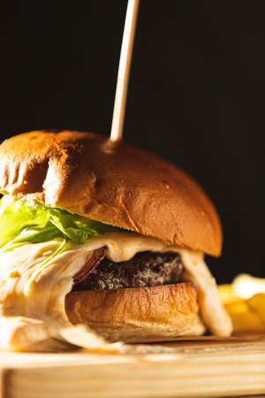 detail of hamburger with cheese poured over the meat on a wooden board skewered with a skewer. premium gourmet burgerの写真素材