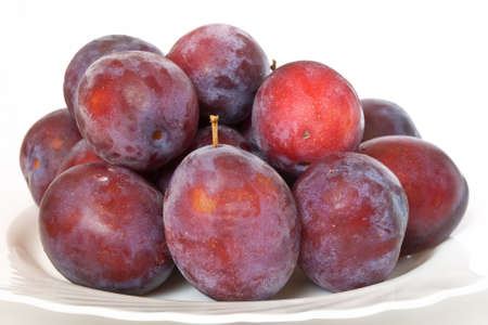 a group of red plums on a white plateの写真素材