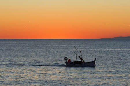 beautiful sunset in Mediterranean sea while a fishing boat returns to portの写真素材