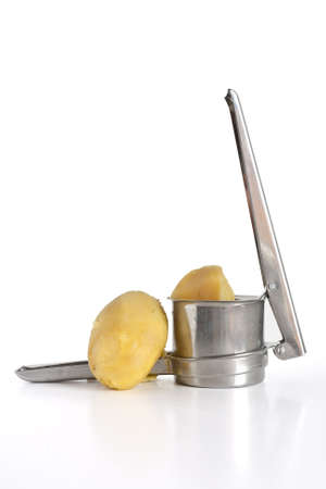 closeup of potato masher with two boiled potatoes isolated on white backgroundの写真素材