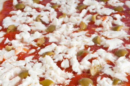 detail of raw pizza with tomato mozzarella and olives