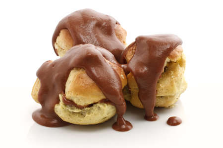 three profiteroles with chocolate sauce over white の写真素材
