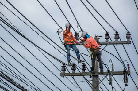 Technicians are repairing high voltage transmission systems on the power poles.のeditorial素材