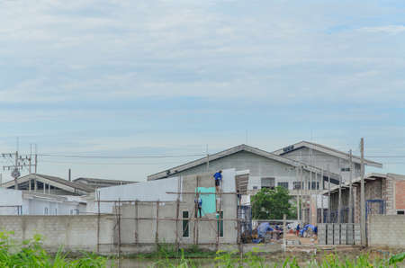 Men's workers are accelerating blue and white paint./New homes under construction / construction are not finished and are under continuous operation.の写真素材