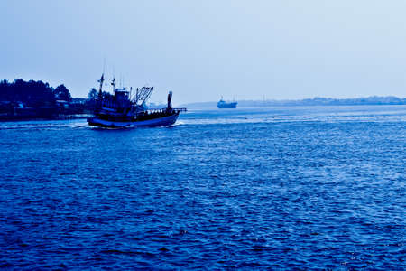 Fishing boats are leaving the shore to the vast sea.の写真素材