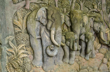 Stone carved of family elephants on the wall from Thailand.の写真素材