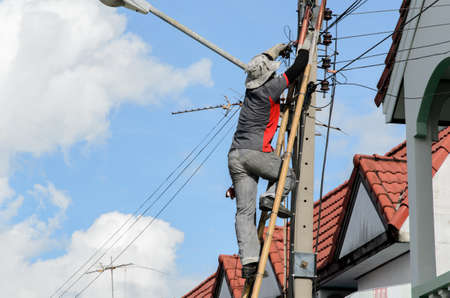 Technician installing Internet cables on the electricity poles in the village.