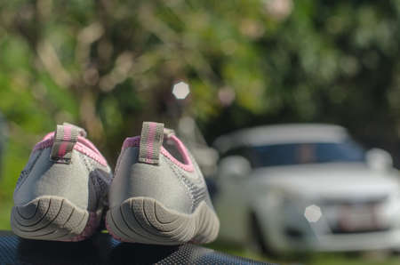 Gray fashion shoes for leisure travel, put on a black cushion on the background of the car park.の写真素材