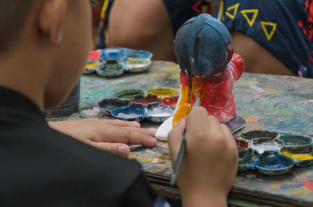 Children painted with brushes on statue plaster dolls placed on wooden boards.の写真素材