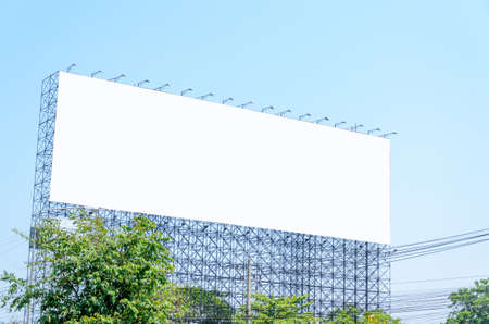 Large blank billboard located on the side of the road with blue sky background.の写真素材