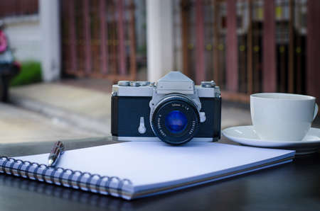 Blank book, coffee cup, pen and retro camera for travel, design ideas.